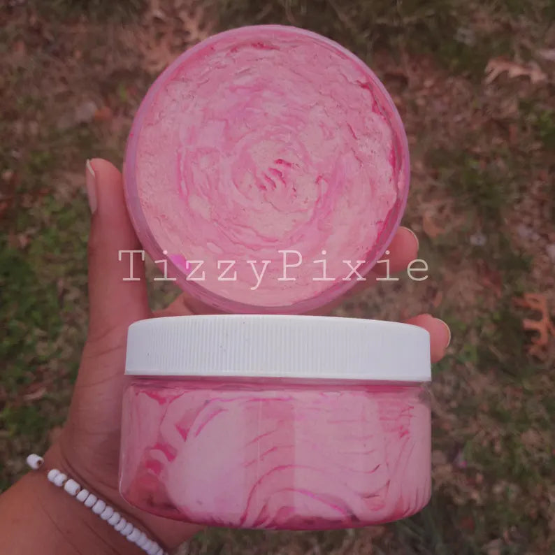 A jar of rose body butter held in a person's hand, with a pink whipped texture visible.